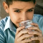 Close-up of a boy drinking from a glass jar outdoors in Cabo San Lucas, Mexico.