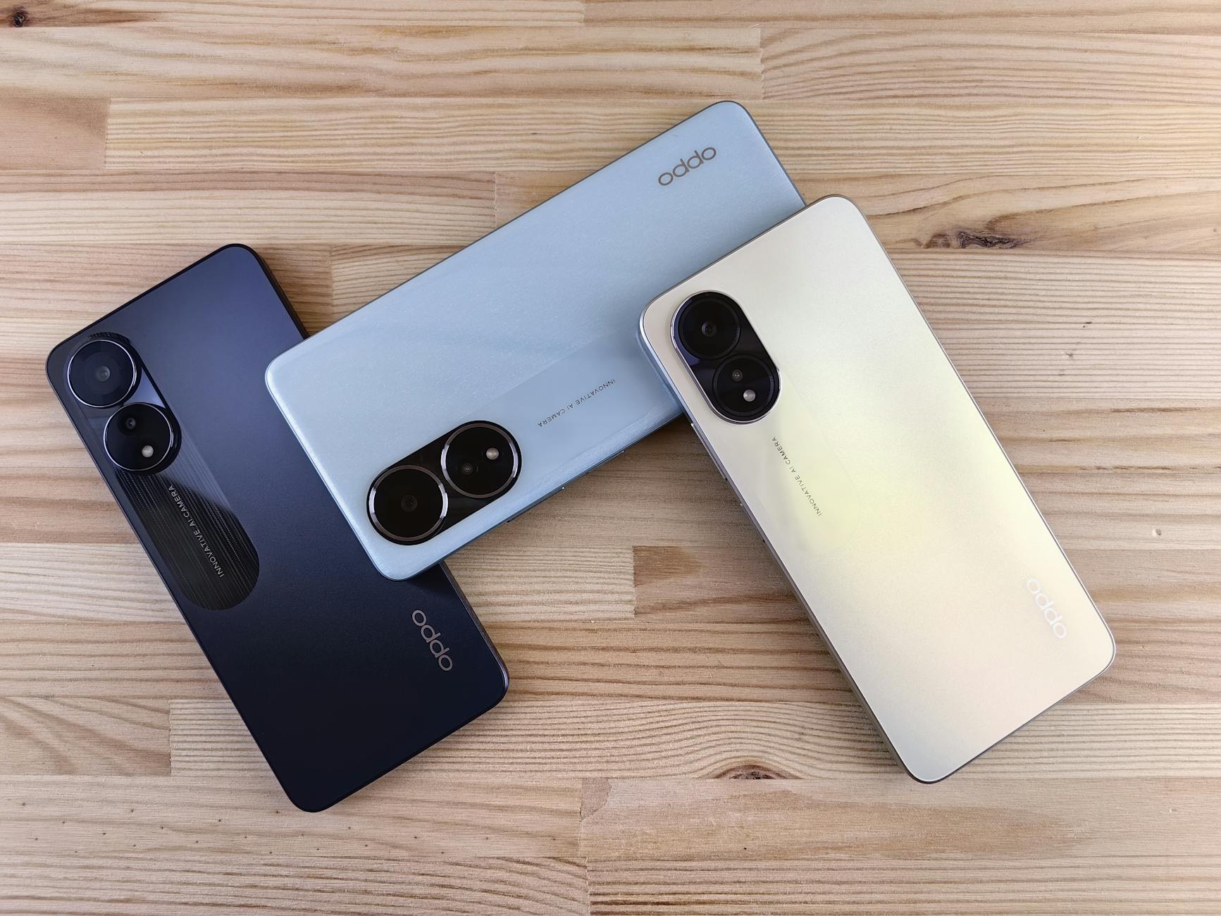 Minimalist flat lay of three smartphones on a wooden surface, showcasing sleek design and camera features.